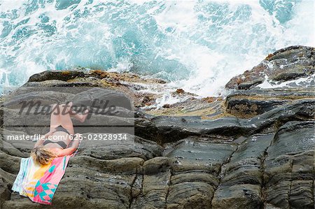High angle view of a woman lying on cliff, RioMaggiore, Cinque Terre, Italian Riviera, Cinque Terre National Park, Vernazza, La Spezia, Liguria, Italy