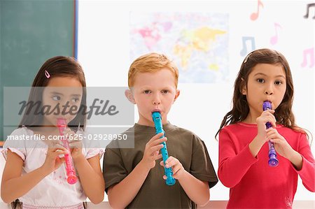 Close-up of a schoolboy with two schoolgirls playing flutes