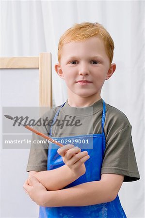 Portrait d'un écolier tenant un pinceau et souriant