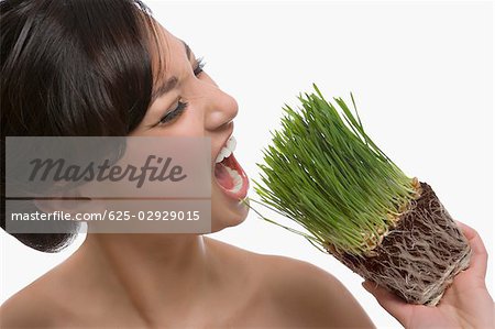 Close-up of a young woman trying to eat wheatgrass