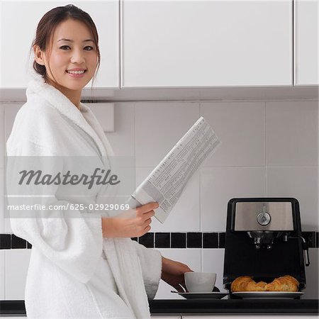 Jeune femme tenant un journal dans la cuisine