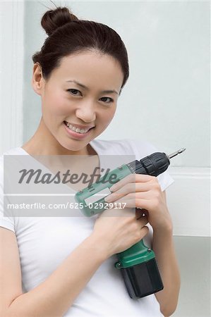 Portrait of a young woman holding a drill and smiling