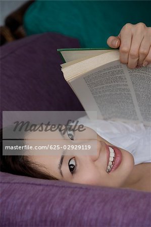 Portrait of a young woman lying down and holding a book