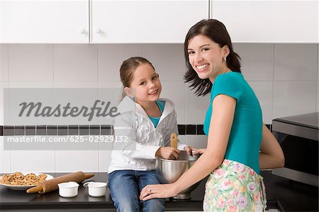Young woman making cookies with her daughter in the kitchen