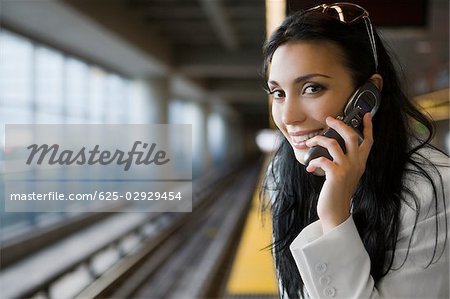 Portrait of a young woman talking on a mobile phone at a subway station