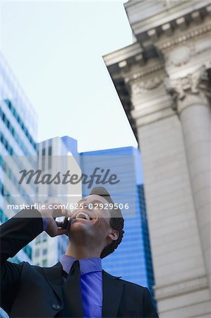 Low angle view of a businessman talking on a mobile phone and laughing