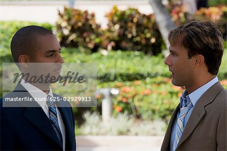 Side profile of two businessmen talking to each other