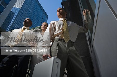Low angle view of two businessmen and a businesswoman standing together
