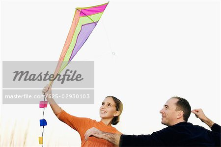 Rear view of a mid adult man with his daughter flying a kite