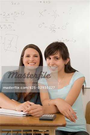 Portrait von ein junges Mädchen und eine Lehrerin im Klassenzimmer sitzen und Lächeln