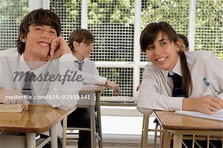 Teenager-Mädchen und ein junger Mann in einem Klassenzimmer sitzen und Lächeln