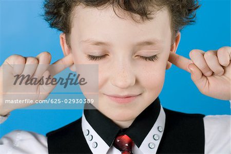 Close-up of a boy with his fingers in his ears