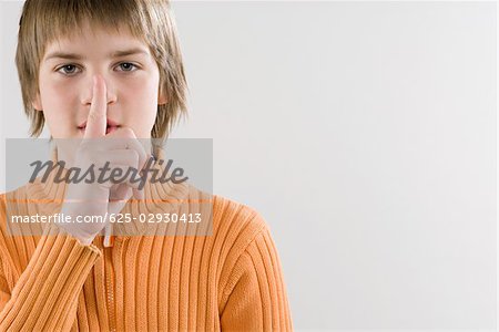 Portrait d'un garçon montrant un geste de silence