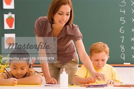 Deux écoliers, avec leur enseignante dans une salle de classe