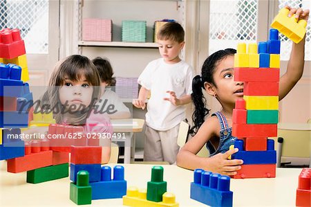 Zwei Mädchen spielen mit Kunststoff Blöcke mit ihren Freunden im Hintergrund