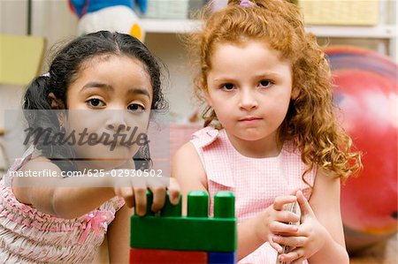 Portrait de deux jeunes filles jouant avec des blocs en plastique