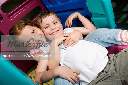 Fille et un garçon assis sur une diapositive et souriant