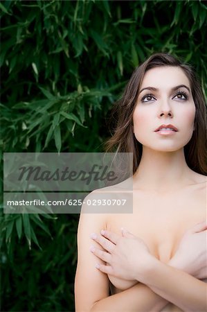 Gros plan d'une jeune femme nue, couvrant ses seins avec ses mains