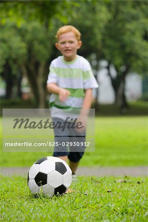 Garçon jouant au football dans un parc