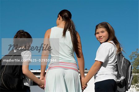 Vue arrière d'une femme adulte mid, main dans la main de ses deux enfants