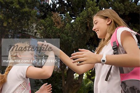 Vue d'angle faible de deux écolières jouer jeu de battements de mains et souriant