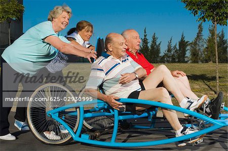 Zwei alte Männer sitzen auf einer Quadracycle und zwei alte Frauen treiben es