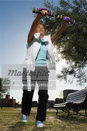 Low angle view of a senior woman exercising with dumbbells in a park