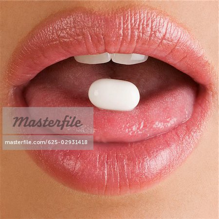 Close-up of a pill on a young woman's tongue