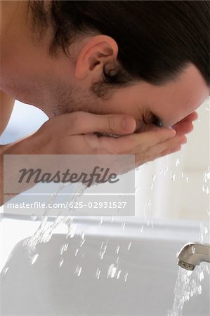 Nahaufnahme eines jungen Mannes, der sein Gesicht waschen