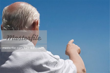 Vue arrière d'un homme senior pointant dans le ciel