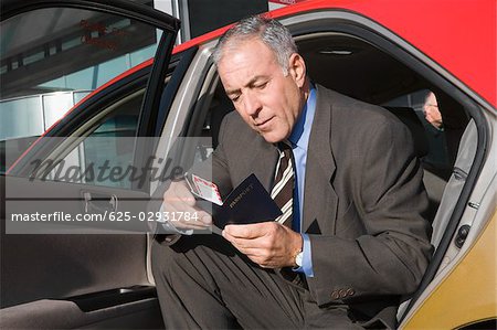 Businessman sitting in a taxi and checking his passport