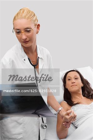 Female doctor holding hand of a patient and looking at an X-Ray report