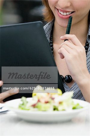 Businesswoman holding a ring binder at a sidewalk cafe