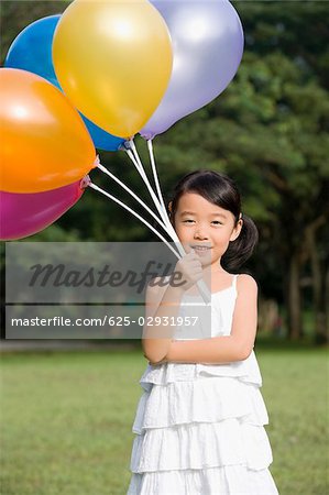 Portrait of a girl holding balloons in a park