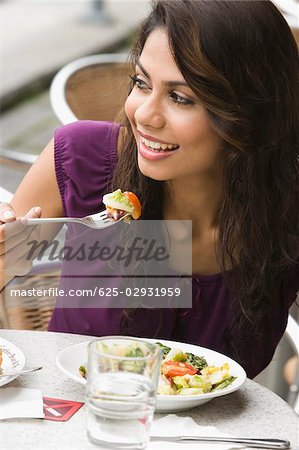 Close-up of a young woman eating salad at a sidewalk cafe