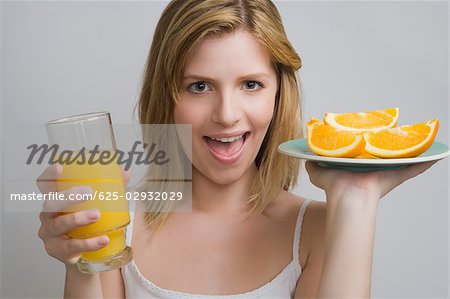 Portrait d'une adolescente qui maintiennent une plaque d'oranges et un verre de jus d'orange