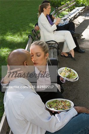 Businesswoman kissing a businessman with two business executives sitting in the background