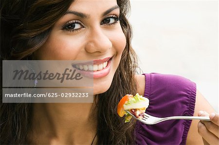 Portrait of a young woman eating salad and smiling