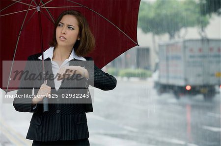 Femme d'affaires qui contrôle le temps pendant la pluie