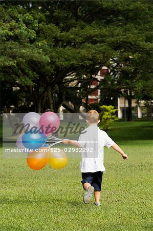 Rückansicht eines jungen mit Ballons in einem park