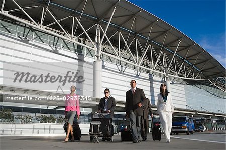 Cinq chefs d'entreprise à pied à l'extérieur d'un aéroport
