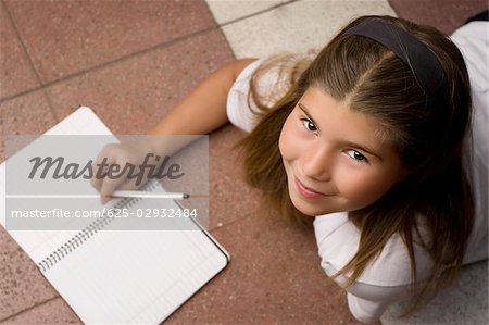 High angle view of a schoolgirl lying on the floor and smiling