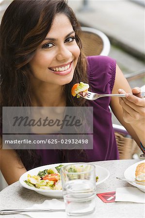 Portrait of a young woman eating salad at a sidewalk cafe