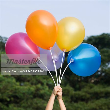 Close-up of a person's hand holding balloons