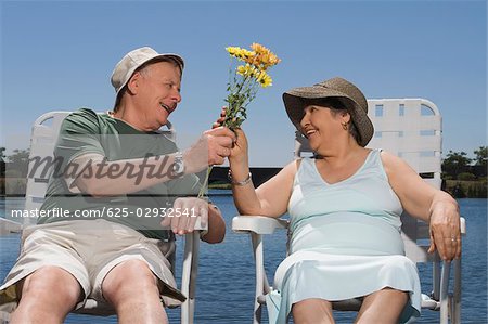 Senior homme donnant un bouquet de fleurs à une femme senior