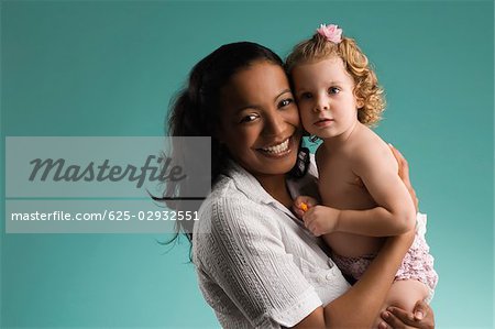 Portrait of a young woman carrying her daughter and smiling