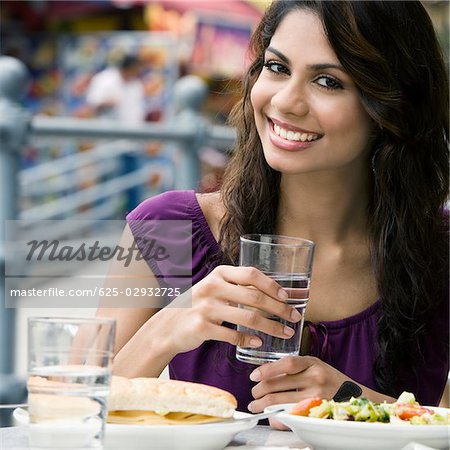 Portrait d'une jeune femme tenant un verre d'eau et souriant