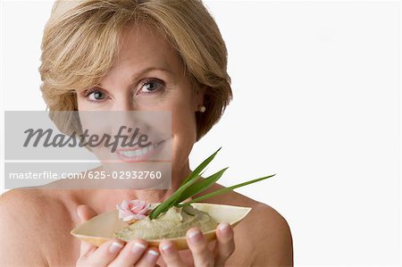 Portrait of a mature woman holding a bowl of face pack