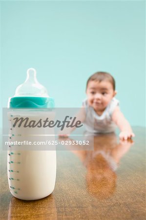 Close-up of a milk bottle with a baby boy in the background