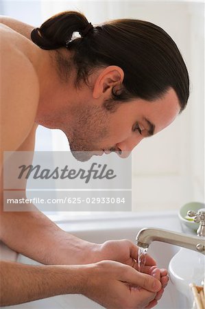Nahaufnahme eines jungen Mannes, der sein Gesicht waschen